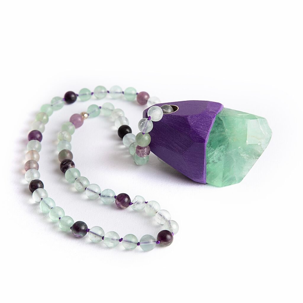Handcrafted Wishkeeper Fluorite pendant necklace on green and purple fluorite beads, artisan jewelry on white background.