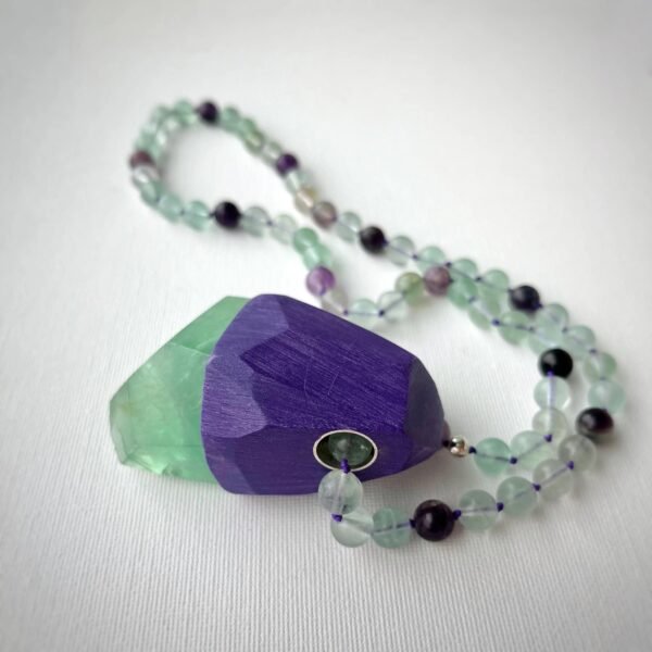 Side view of Wishkeeper pendant necklace showing green and purple fluorite beads and geometric fluorite stone pendant.